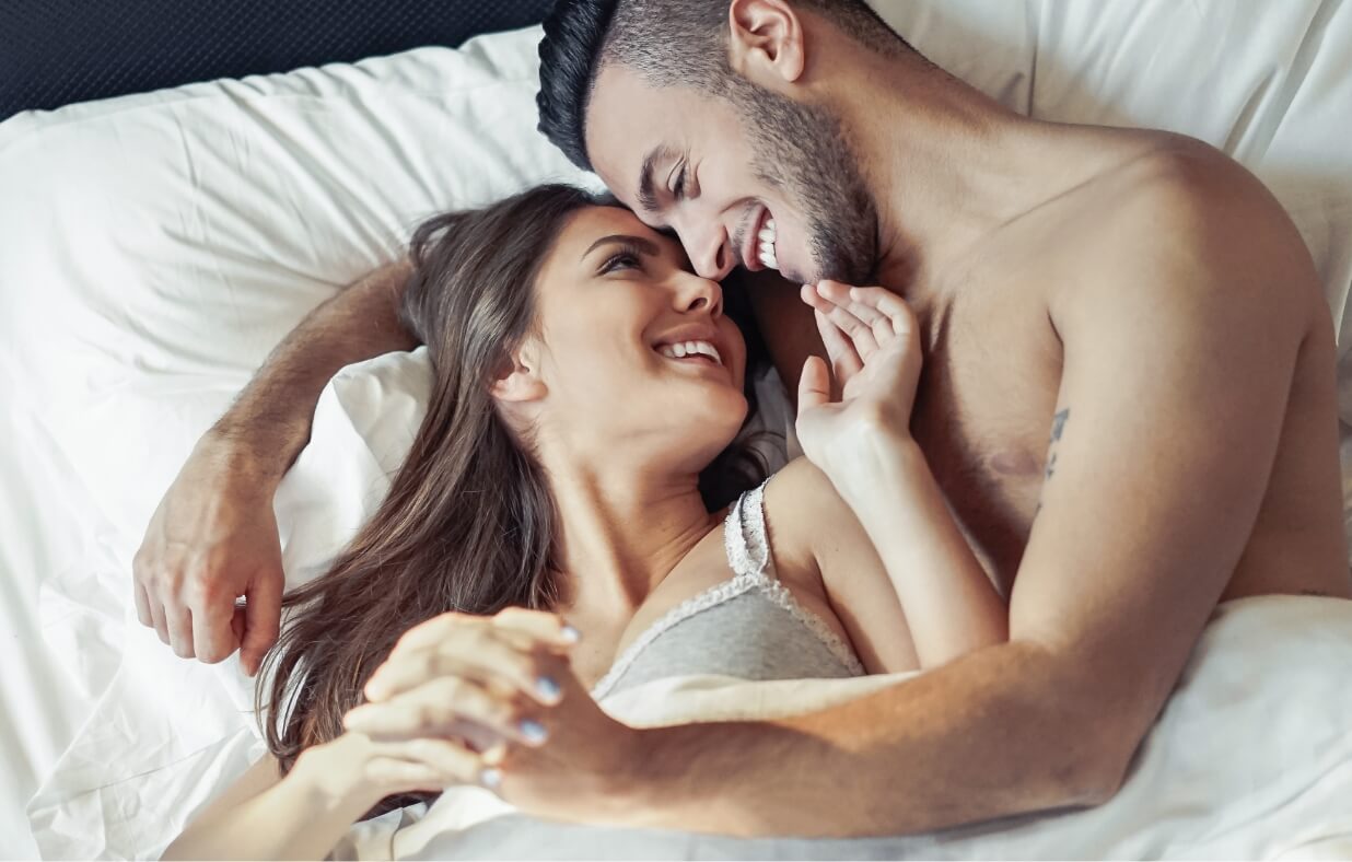 A couple embracing while resting in bed.