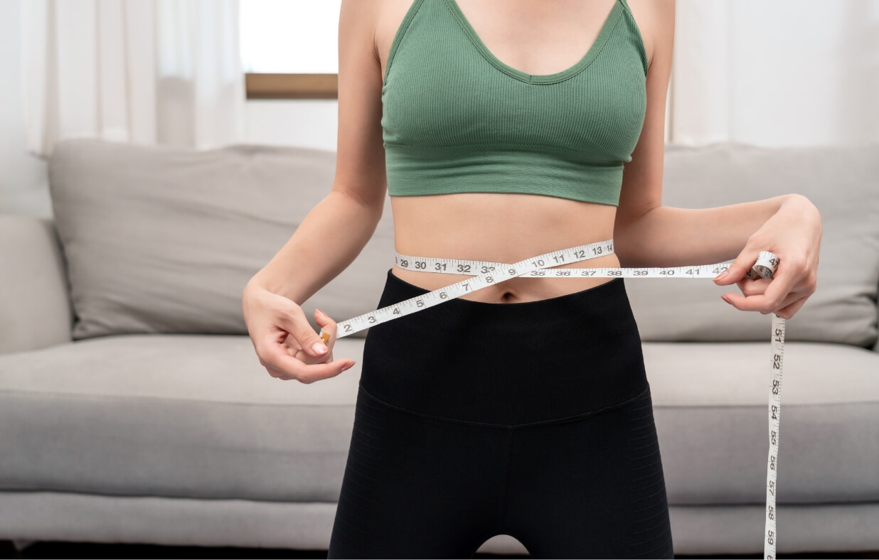 Woman holding a tape measure around her waist.