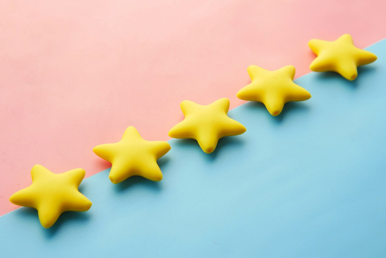 Five yellow star shapes arranged on a pink and blue surface.