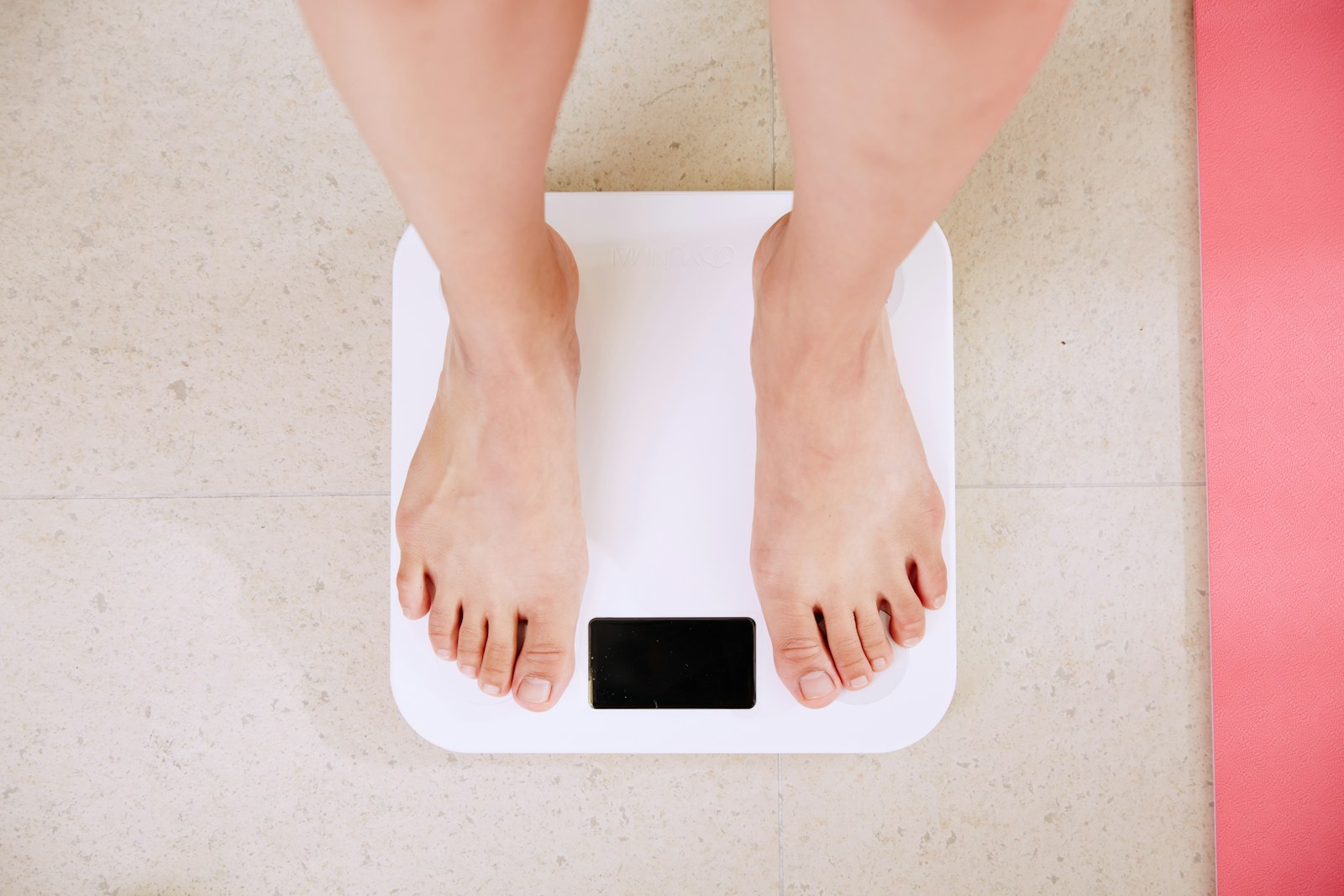 Person stands on a white digital bathroom scale.