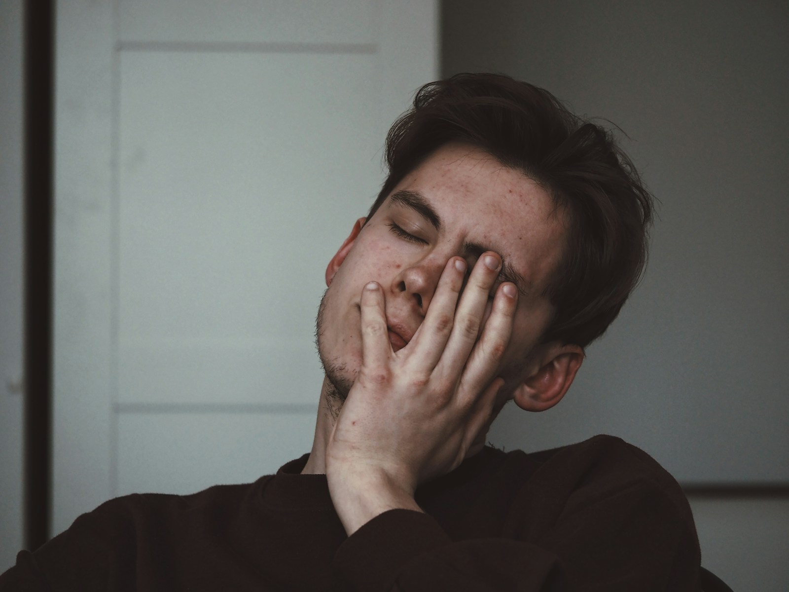 An adult man rests a hand across his face.