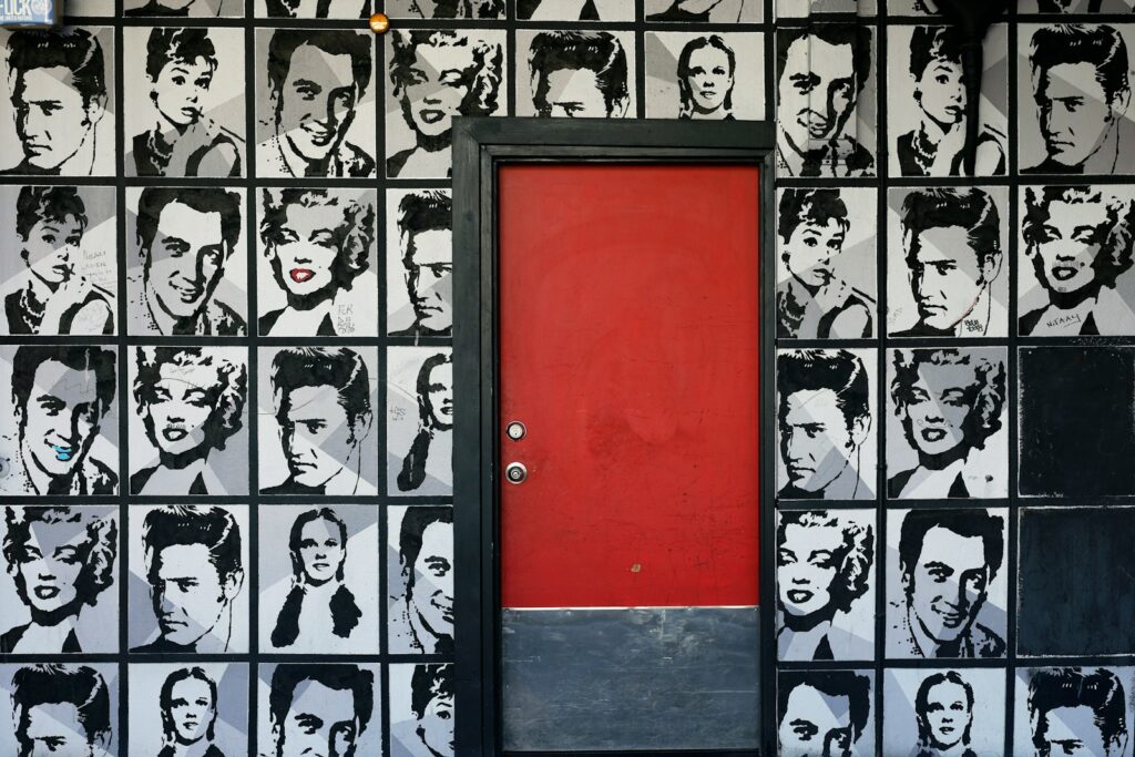 a red door is in front of a wall with black and white pictures of men