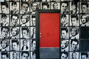 a red door is in front of a wall with black and white pictures of men