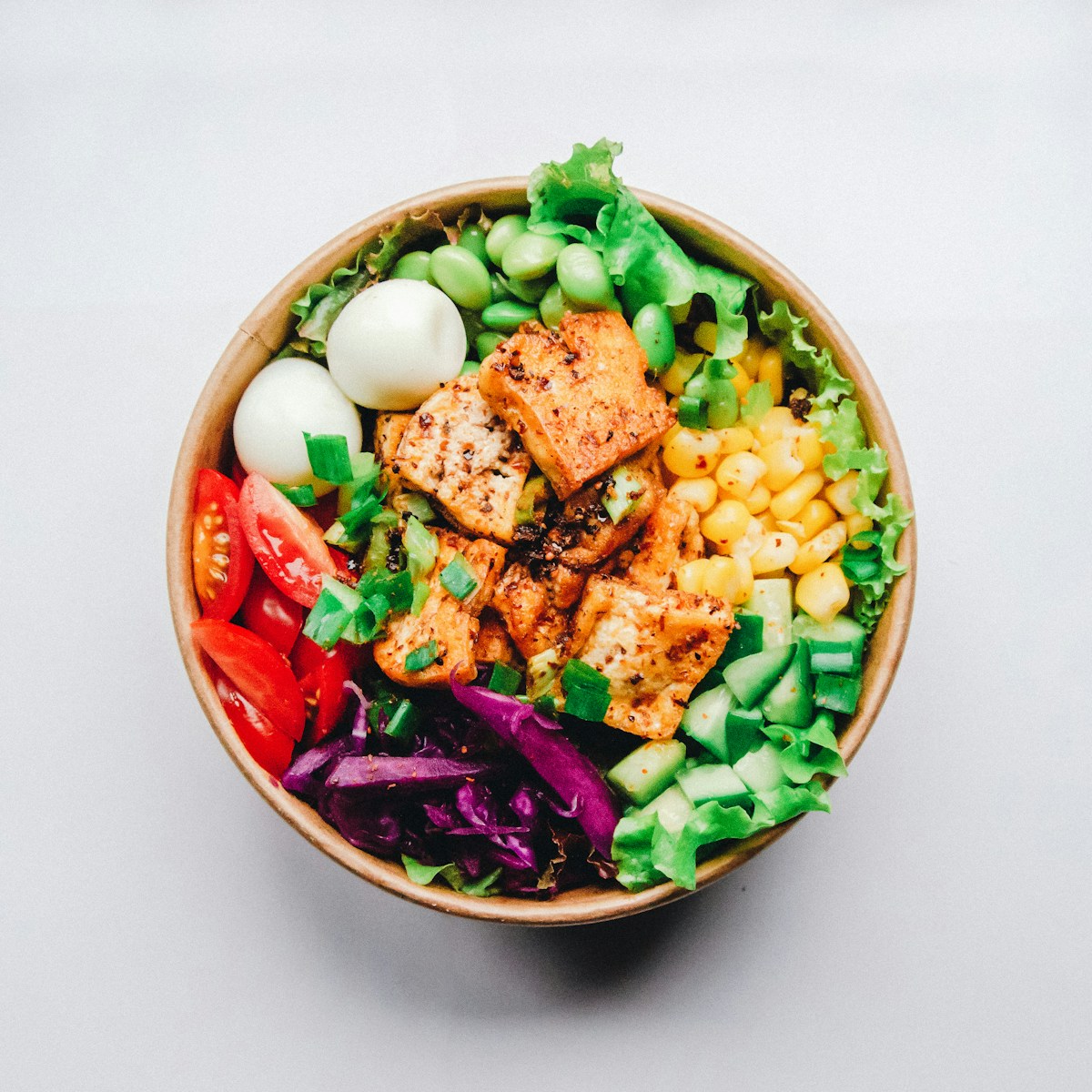 Overhead view of a bowl with vegetables and other meal components.