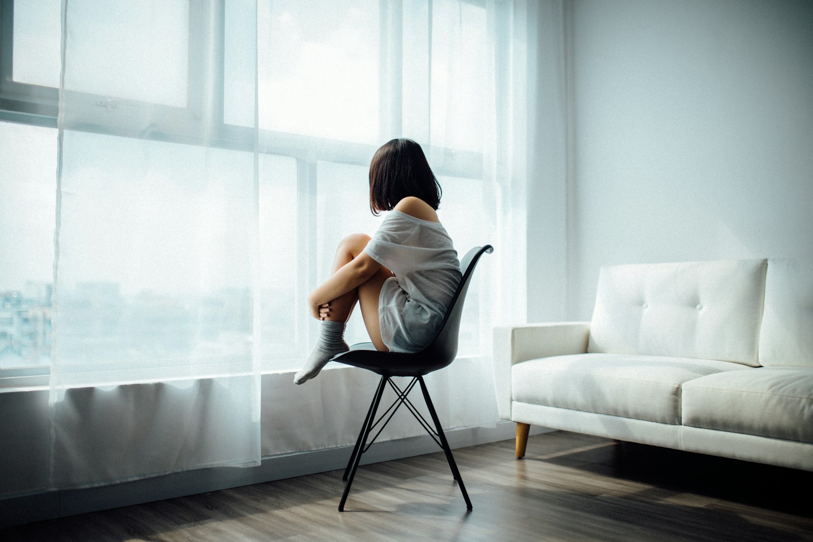 An adult sitting beside a bright window in a quiet room.