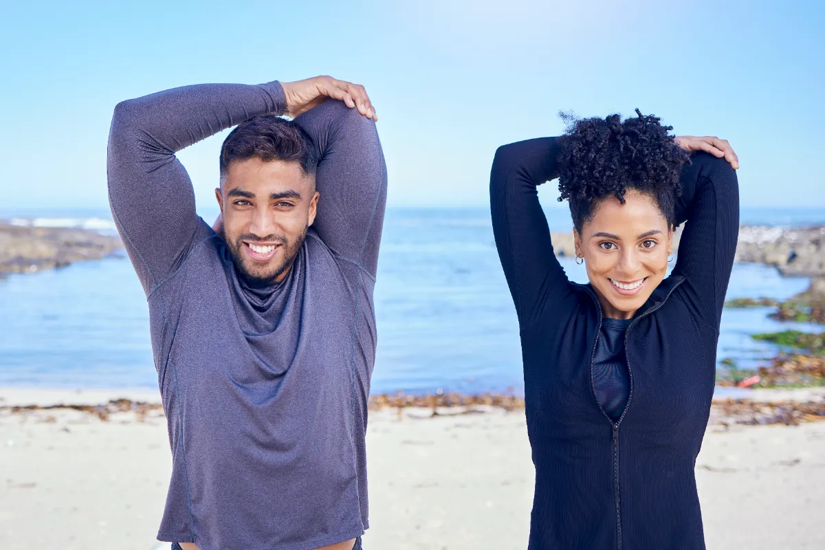 Two adults stretching beside the water