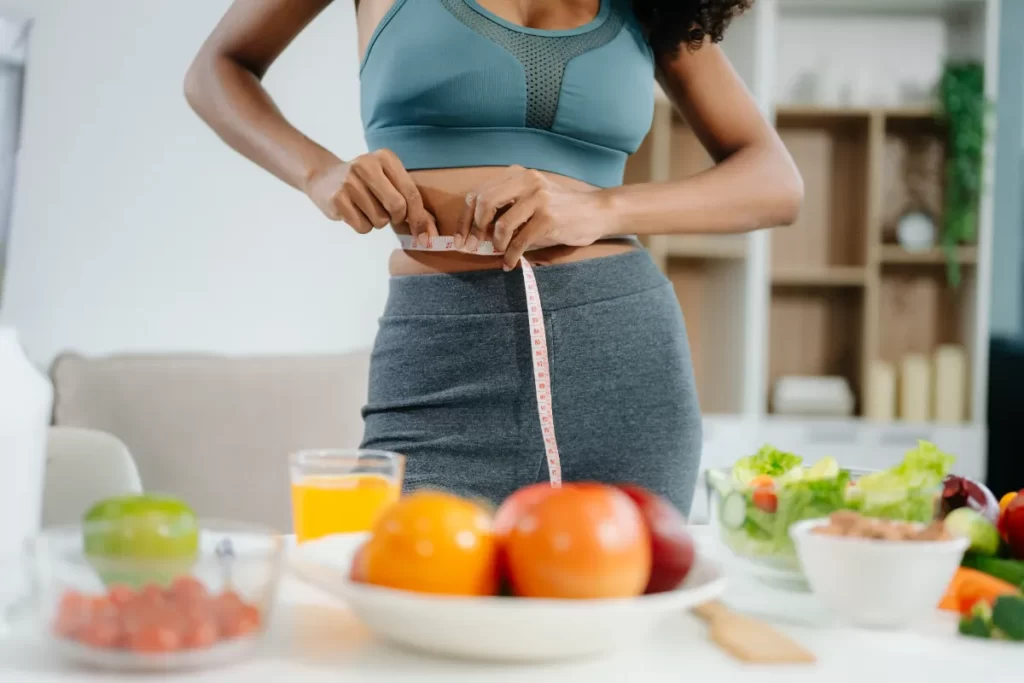 smiling-woman-measuring-waist-holding-green-apple-2026-03-25-09-14-20-utc
