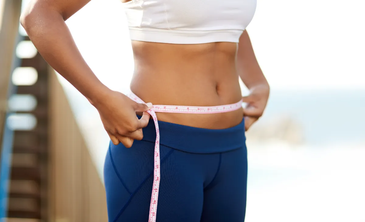 athletic woman measures her waist with tape measur utc