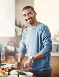 cheerful man cutting vegetables in bright kitchen utc