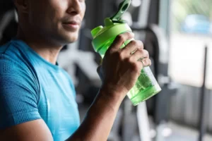 focused fitness man holding shaker bottle in gym utc
