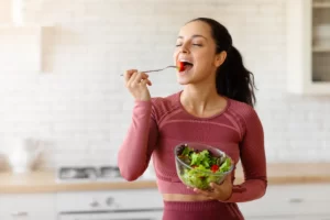 healthy woman enjoys a salad in kitchen utc