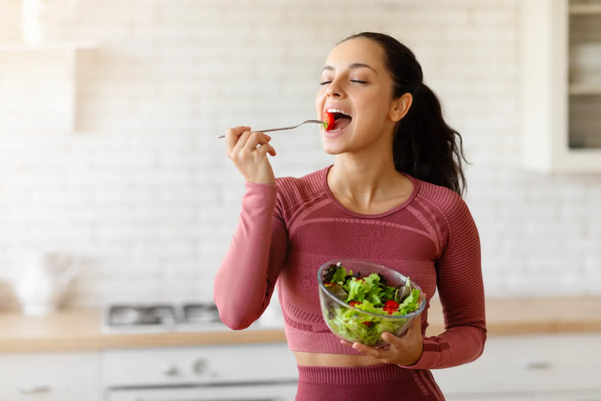 Woman eating a salad in a kitchen