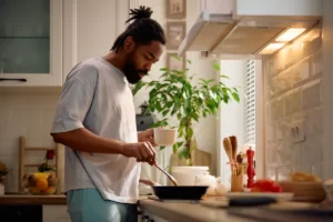 man cooking food at home in kitchen utc