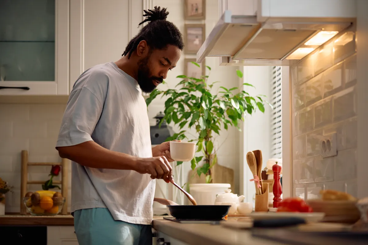 man cooking food at home in kitchen utc
