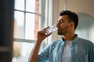 man hydrating with fresh water in bright home utc