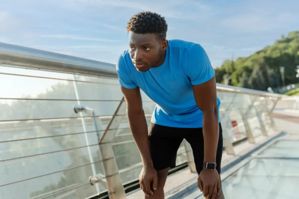 man resting after exercising outdoors on bridge utc