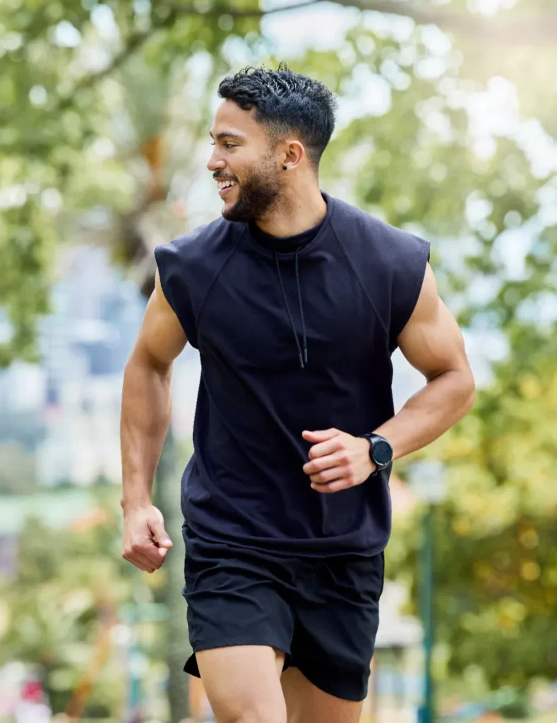 man running in park wearing black athletic gear utc
