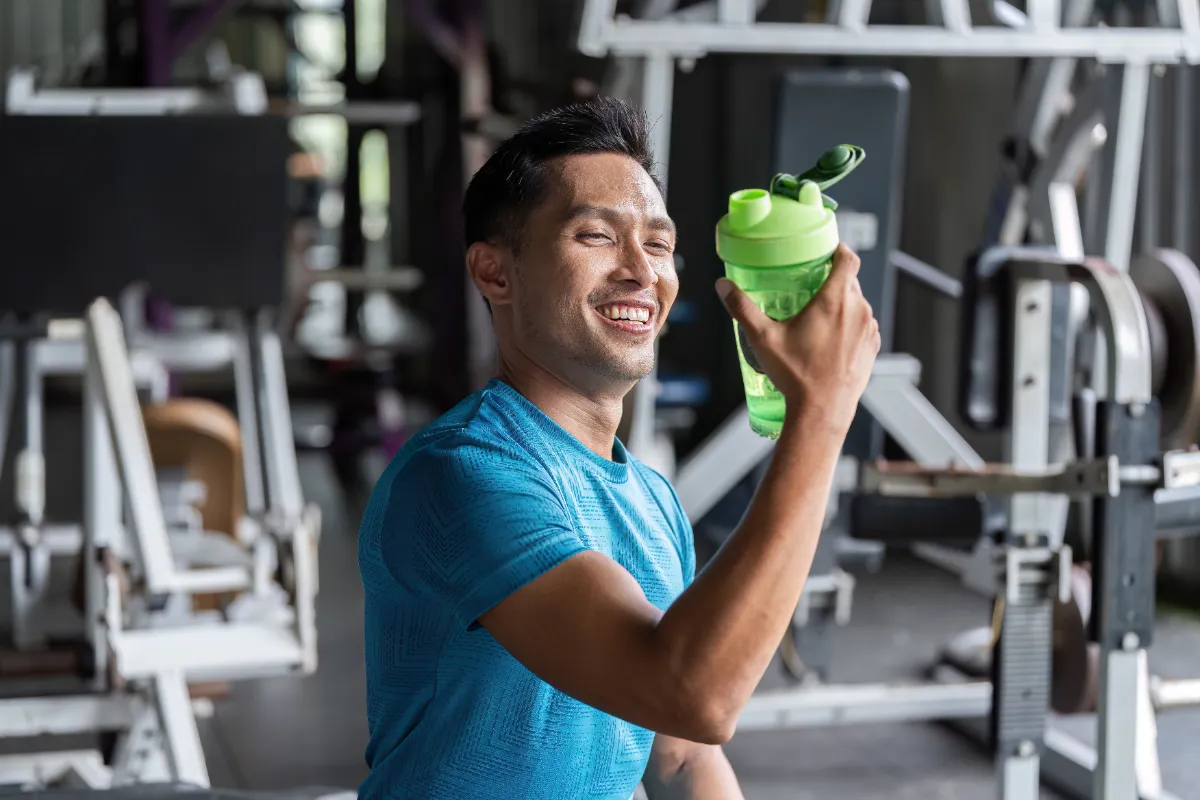 man smiling holding drink in modern gym utc