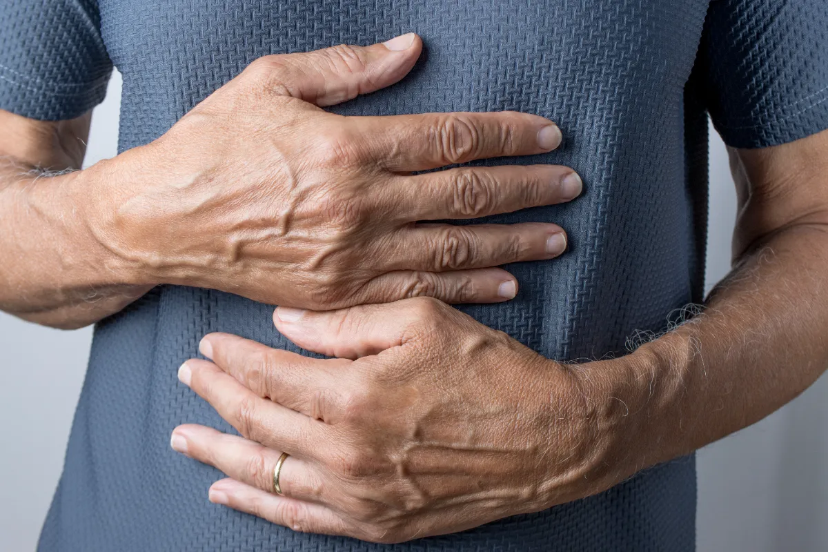 Close view of an adult's hands resting across the abdomen.