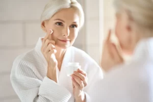 mature woman applying cream to her face utc