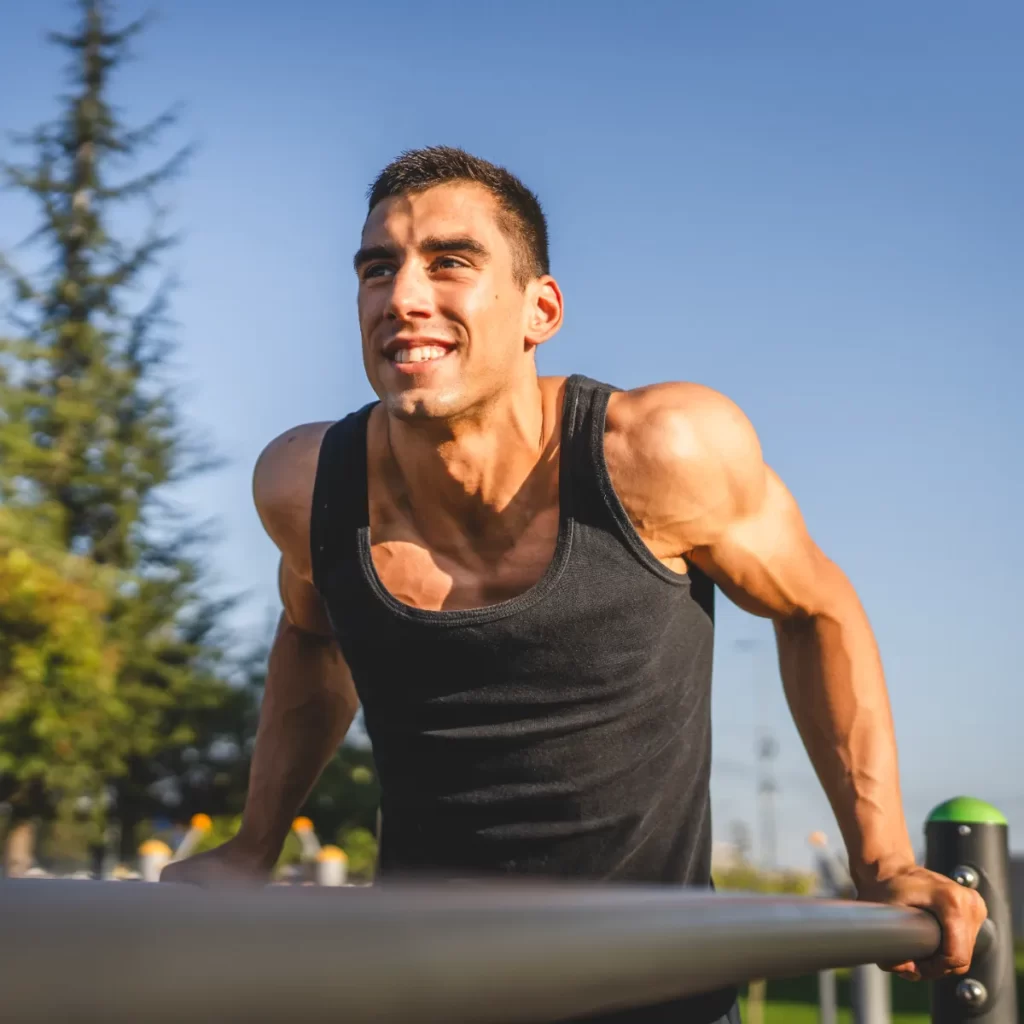 muscular young man doing dips at an outdoor gym utc