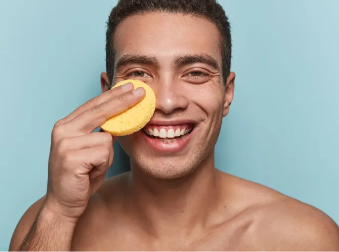 smiling-man-cleansing-face-with-yellow-sponge-2026-01-07-01-11-02-utc