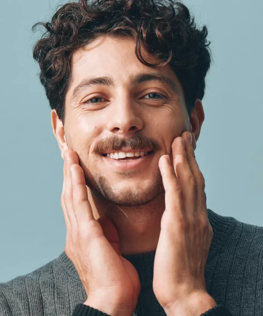 smiling man in gray sweater posing in studio utc