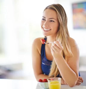 woman enjoys fresh strawberries and orange juice utc