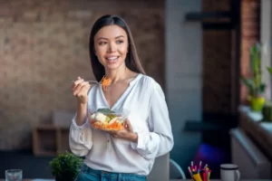 young woman enjoys healthy salad in office utc