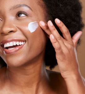 young woman applying cream to her face utc