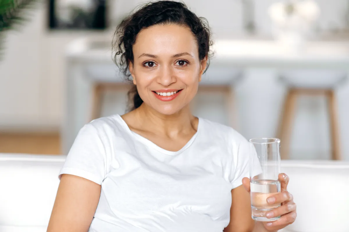 A woman holding a glass of water indoors