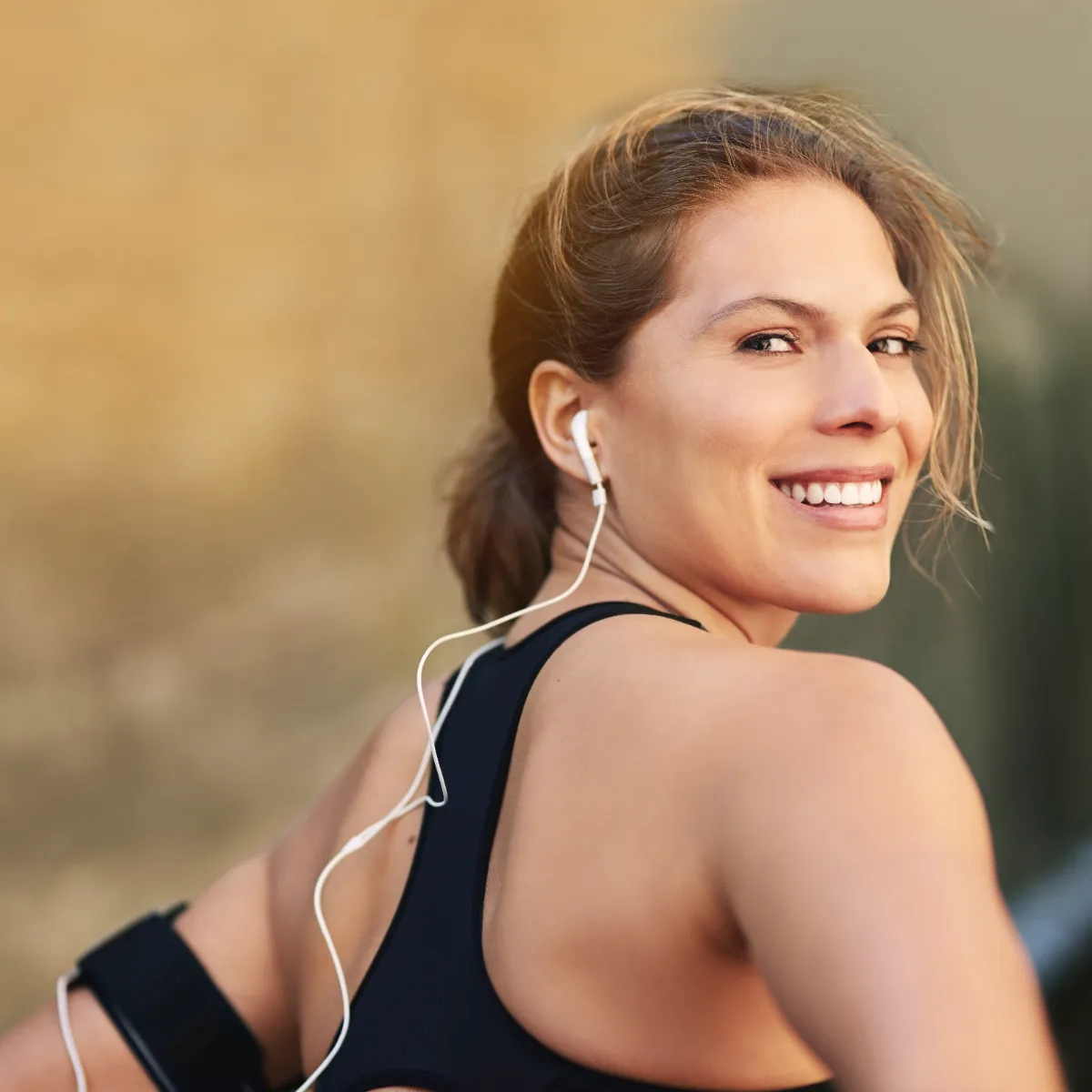 An adult wearing sports clothing and headphones outdoors.