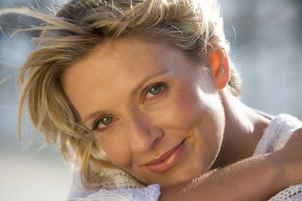 smiling woman portrait with blonde hair and wind utc