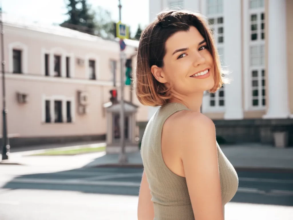 smiling woman poses in city street on sunny day utc