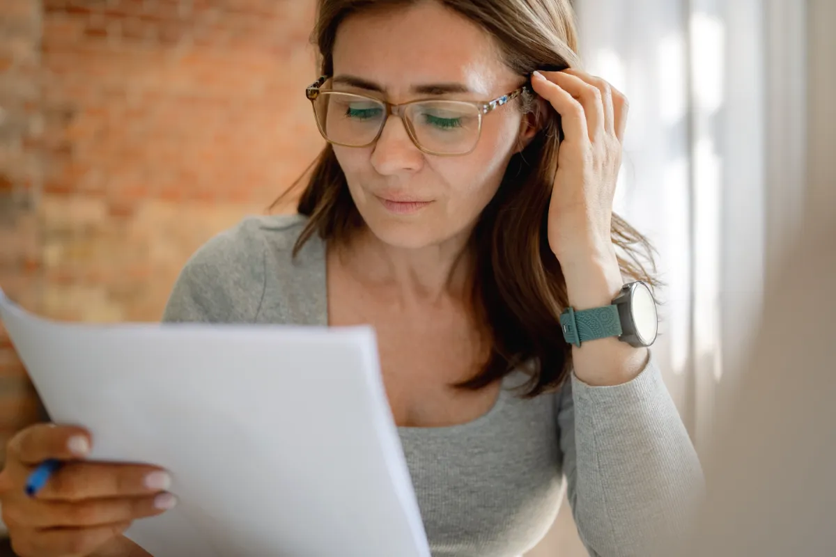 thoughtful woman wearing glasses reading a documen utc