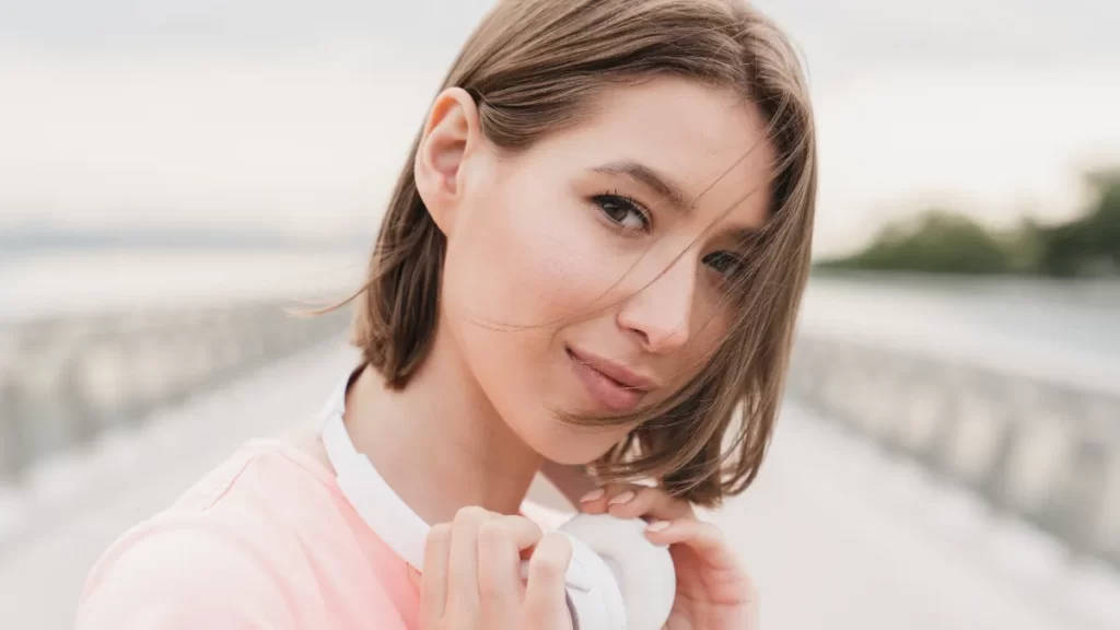 woman poses with headphones around her neck utc
