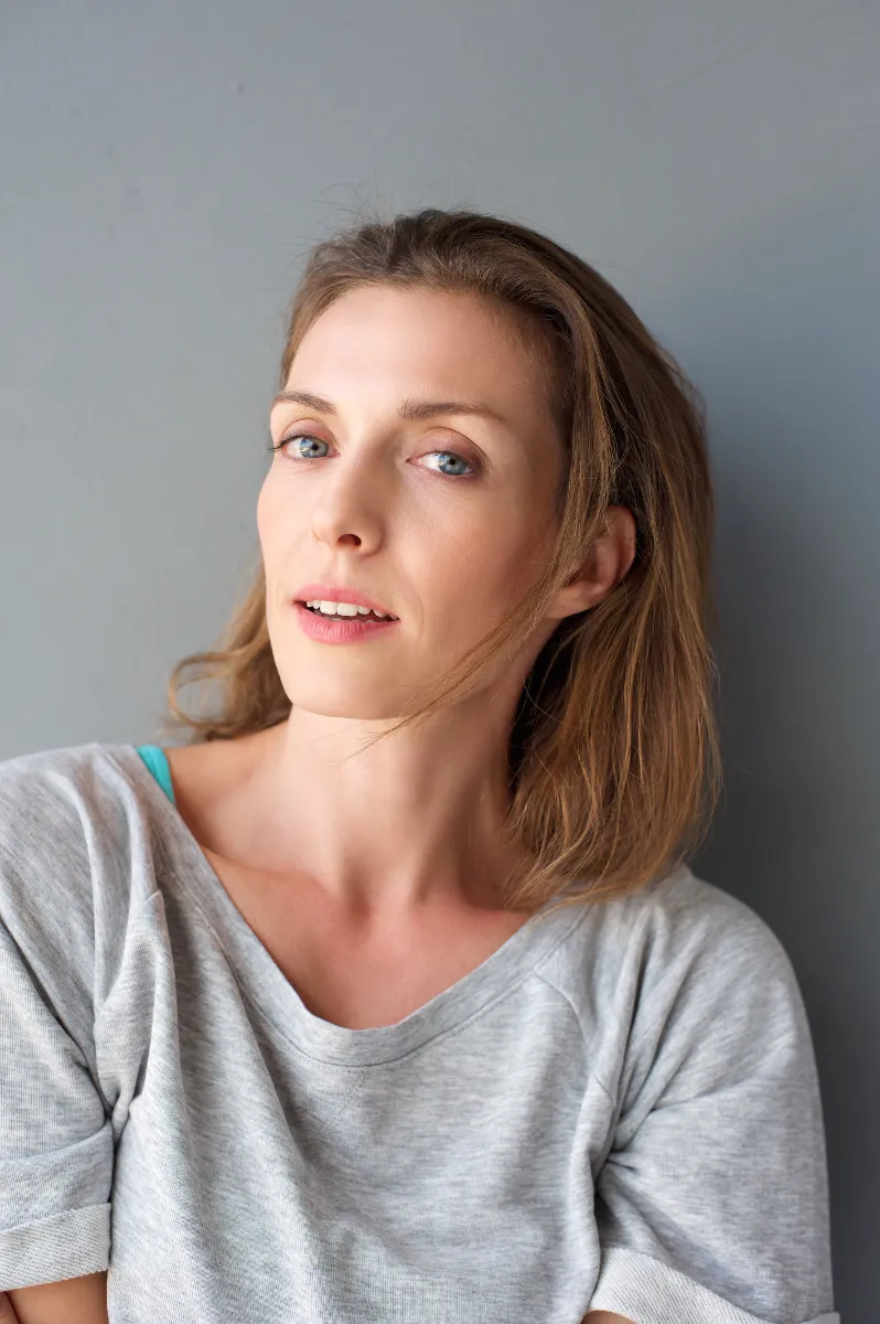 An adult wearing a gray shirt indoors.