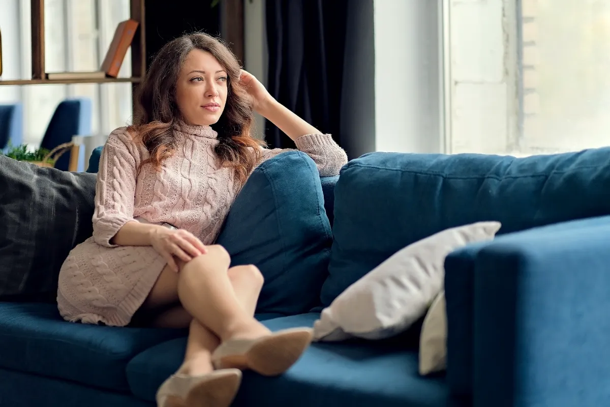 An adult seated on a blue sofa indoors.
