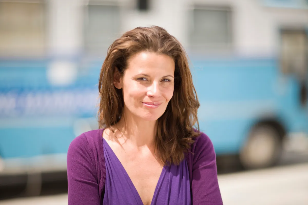 woman smiles in front of blue vehicle utc
