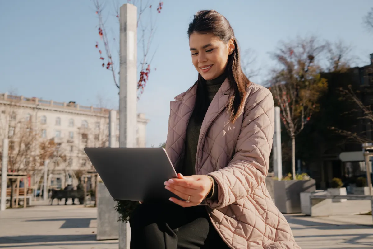 An adult using a laptop while seated outdoors.