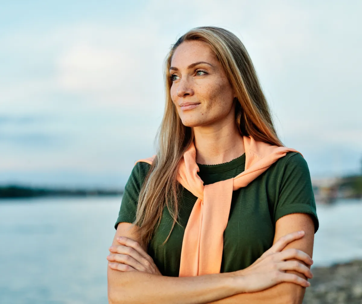 woman with blonde hair on river shoreline utc