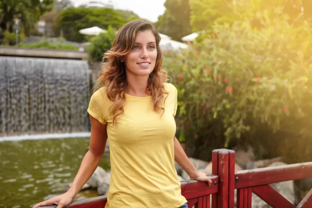 woman with flowing hair poses near waterfall utc