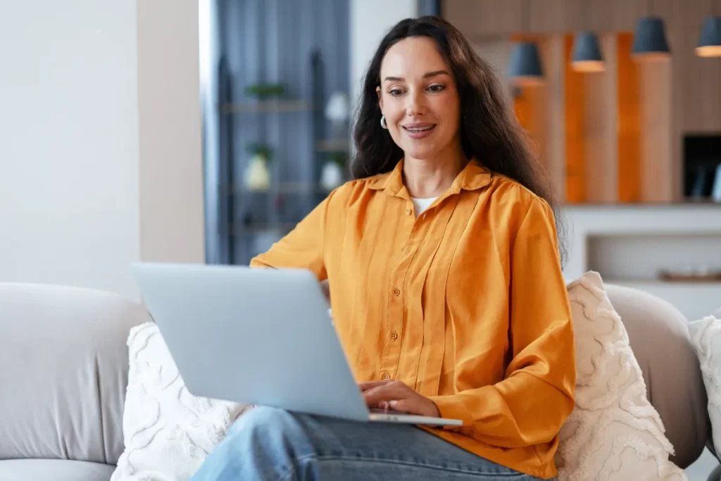 woman working from home with laptop on sofa utc