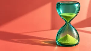 Conceptual hourglass with teal glass and lime-colored sand on a coral surface; not a measured clearance clock.