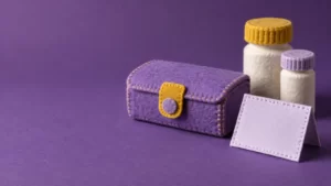 Violet and mustard felt illustration of a medicine organizer, containers and a blank card.