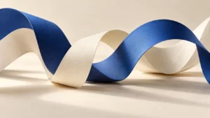 Cobalt and ivory paper ribbons curve across a warm ivory surface.